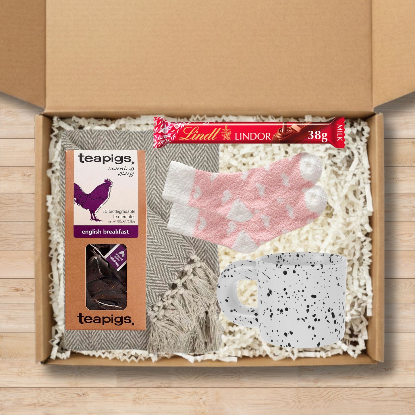 Gift box with a throw blanket, teapigs tea, Lindt chocolate, a mug, and socks