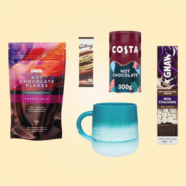 A range of products including a blue mug, GNAW hot chocolate flakes, a GNAW hot chocolate spoon, Costa hot chocolate and a Galaxy instant hot chocolate sachet, arranged on a light yellow background.