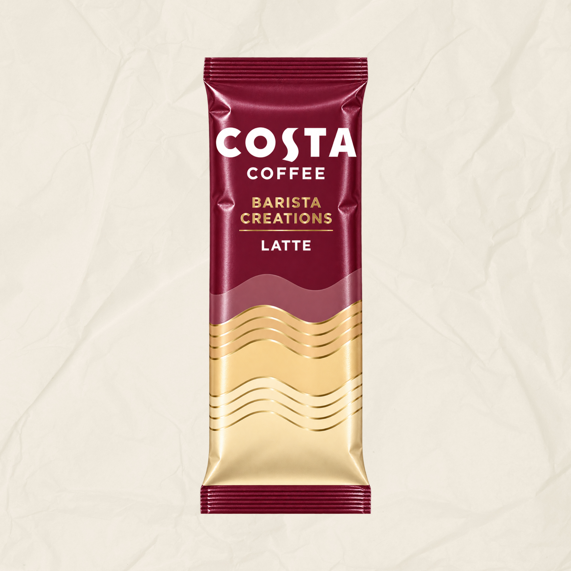 A single Costa Coffee Barista Creations Latte sachet standing upright on a textured off-white background. The packaging is deep burgundy with white and gold lettering and a gold wave pattern near the bottom.