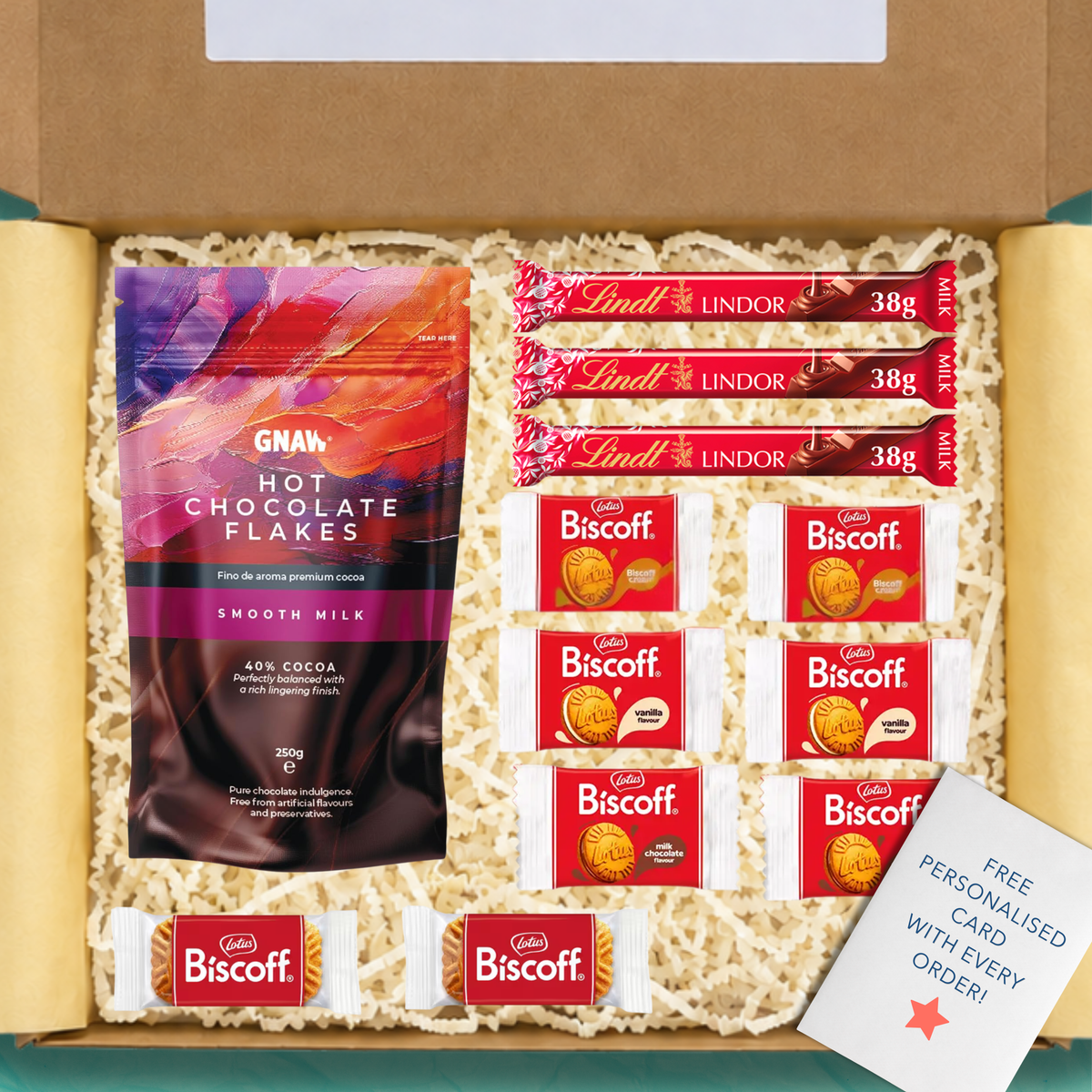 An open gift box with yellow tissue paper and yellow shredded paper packaging containing a series of items: A pack of GNAW hot chocolate flakes, 3 Lindt Lindor chocolate bars, a selection of Lotus Biscoff biscuits, and a free personalised card.