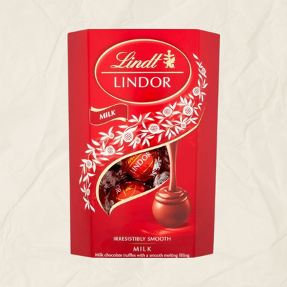 A red Lindt Lindor Milk chocolate box with a clear window showing wrapped milk chocolate truffles inside, set against a light textured background.