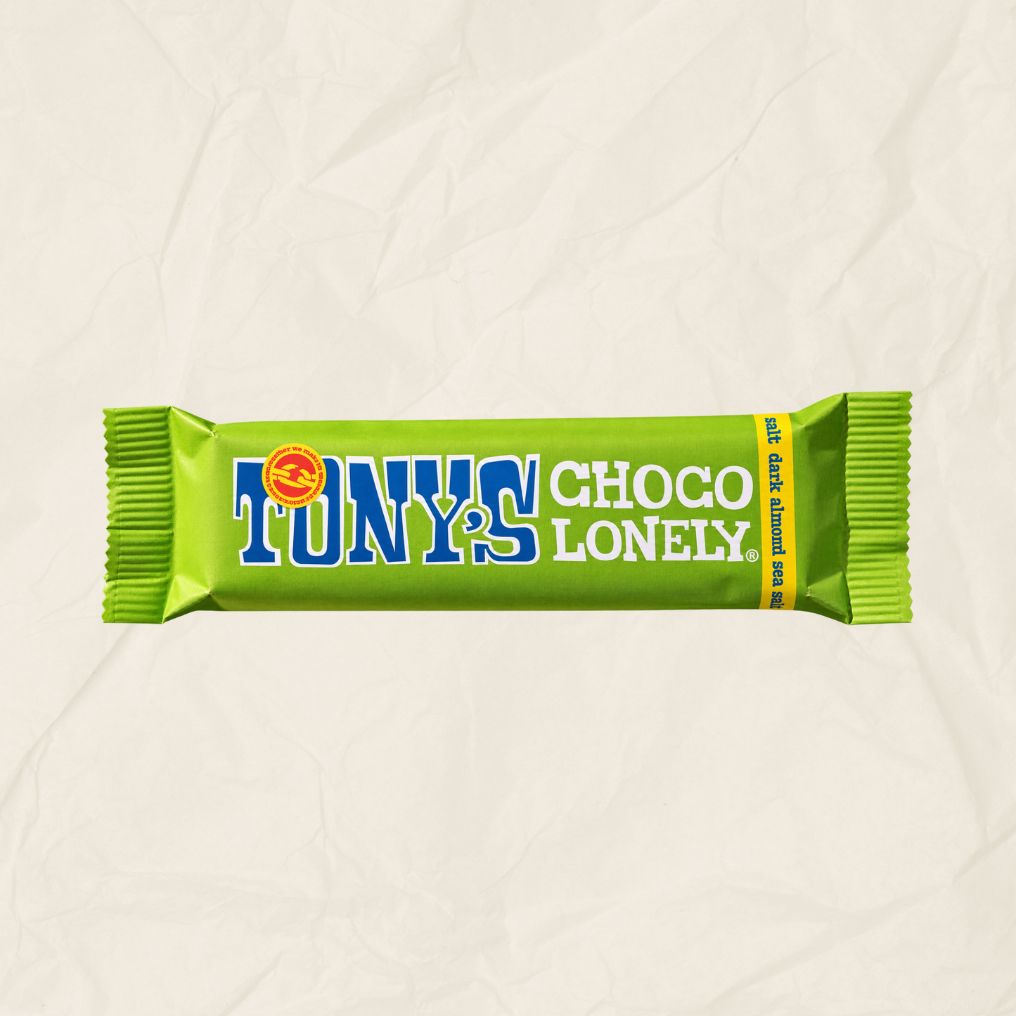 A single Tony's Choco Lonely chocolate bar wrapper in bright lime green, with blue and white lettering, centered on a light beige crumpled paper background.