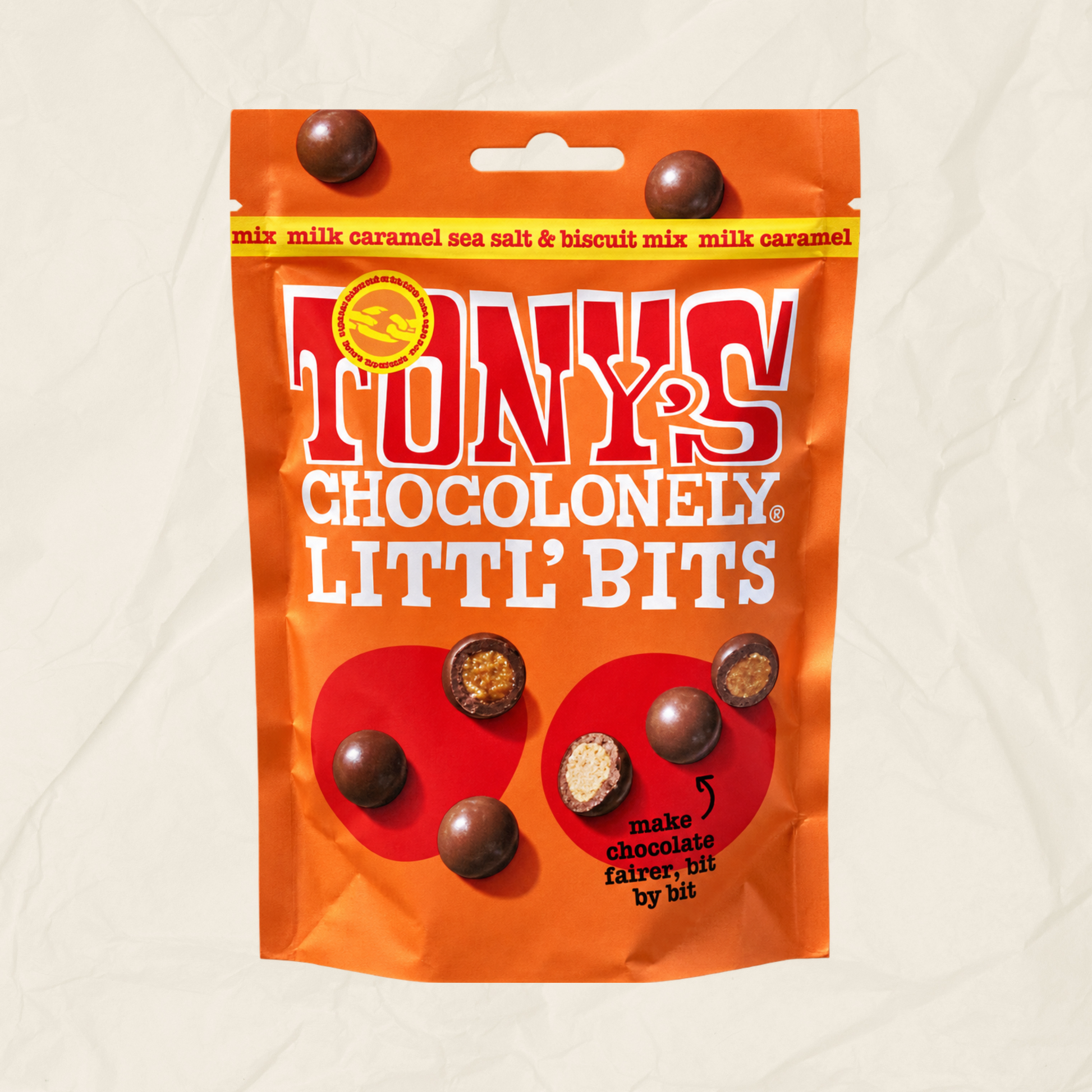 A bag of Tony's Chocolonely Litt' Bits chocolate mix, in an orange pouch with red and white branding, against a light beige textured background.