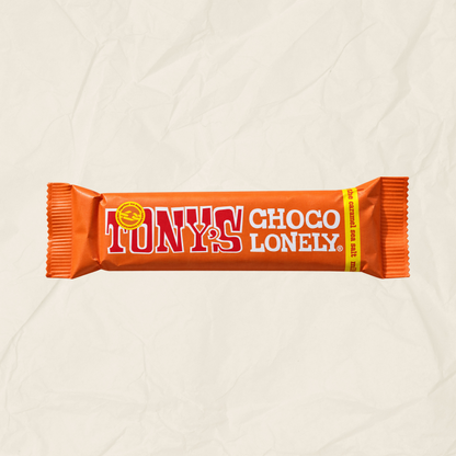A single Tony's Choco Lonely chocolate bar in its signature orange wrapper, displayed horizontally against a textured, crumpled off-white paper background.