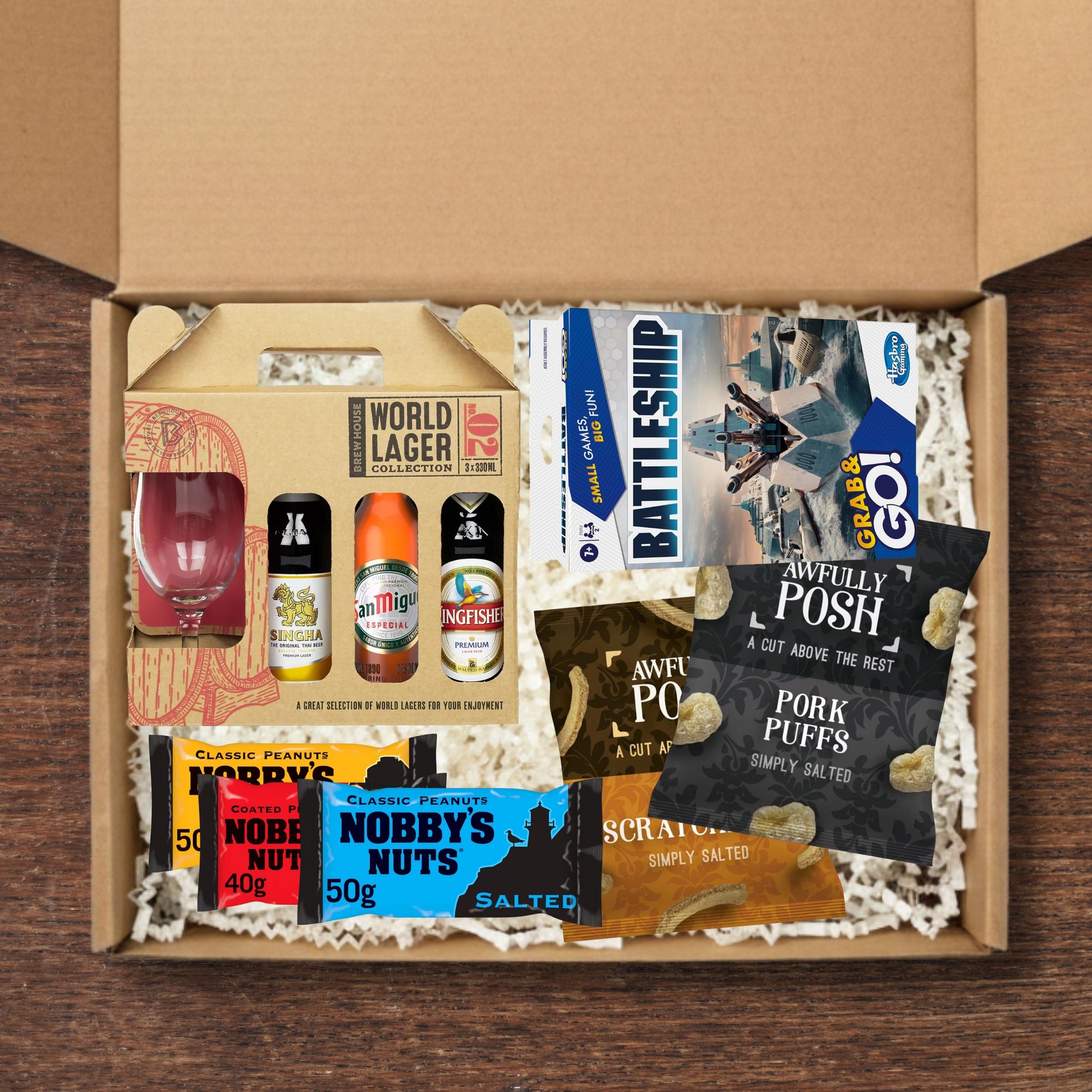 Gift box containing a lager gift set, battleships board game, awfully posh snacks, and nobby's nuts.