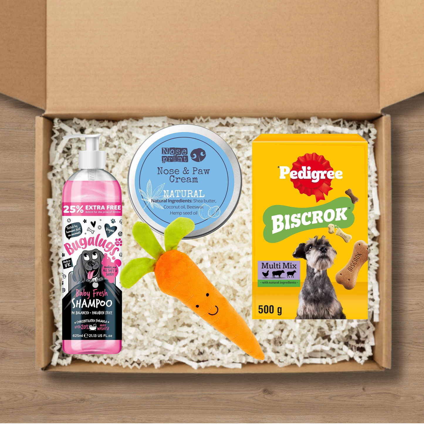 Dog care gift box including shampoo, nose and paw cream, Pedigree Biscrok, and a carrot chew toy.