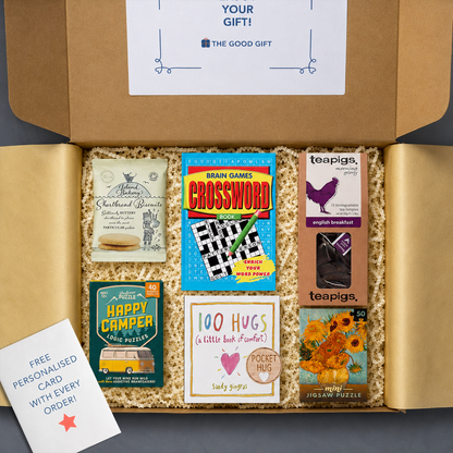 Gift box containing Teapigs english breakfast tea, a 100 Hugs book, shortbread biscuits, a Happy Camper game, a masterworks jigsaw puzzle, a crossword book, and a pocket hug