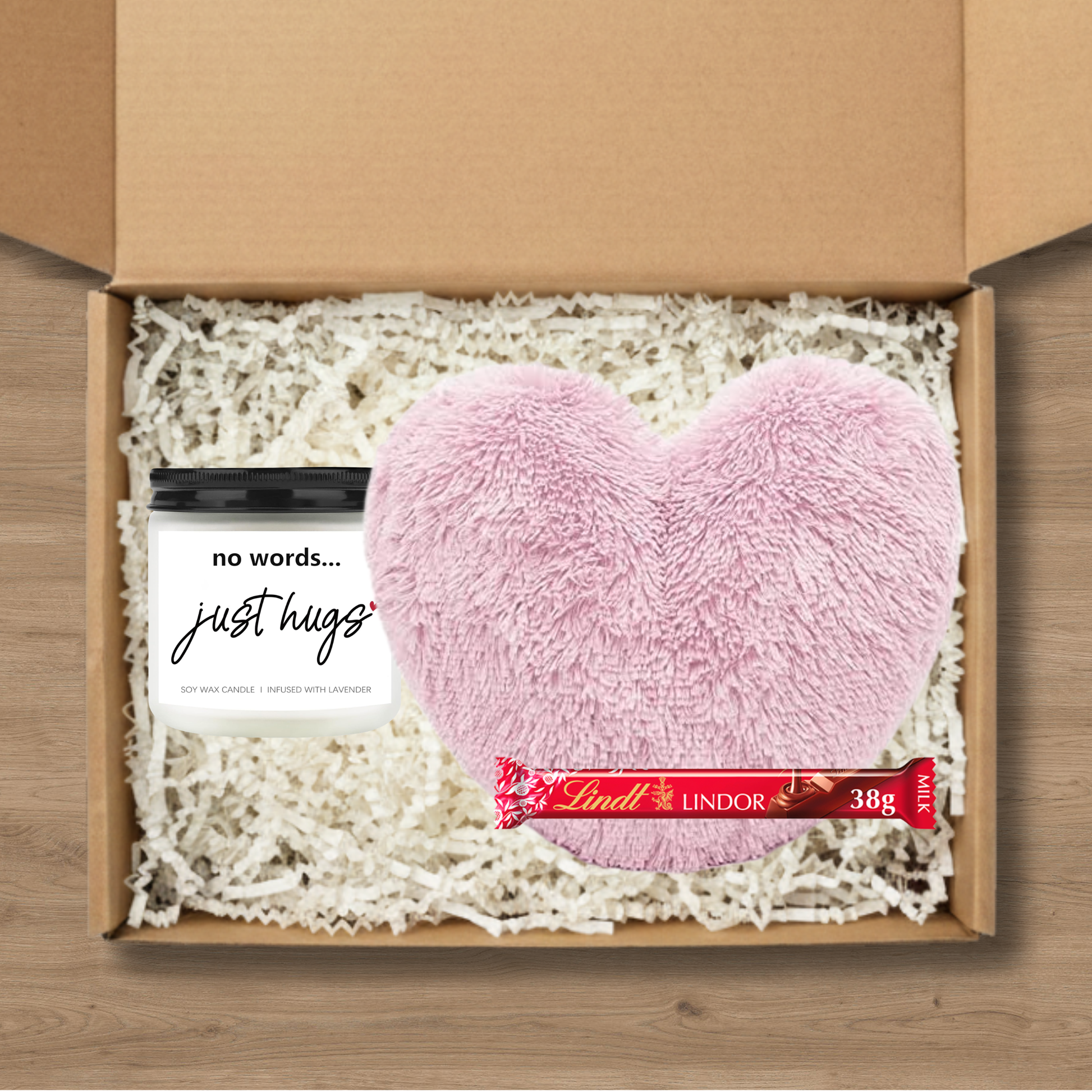 Gift box with pink heart-shaped cushion, candle, and Lindt Lindor chocolate bar
