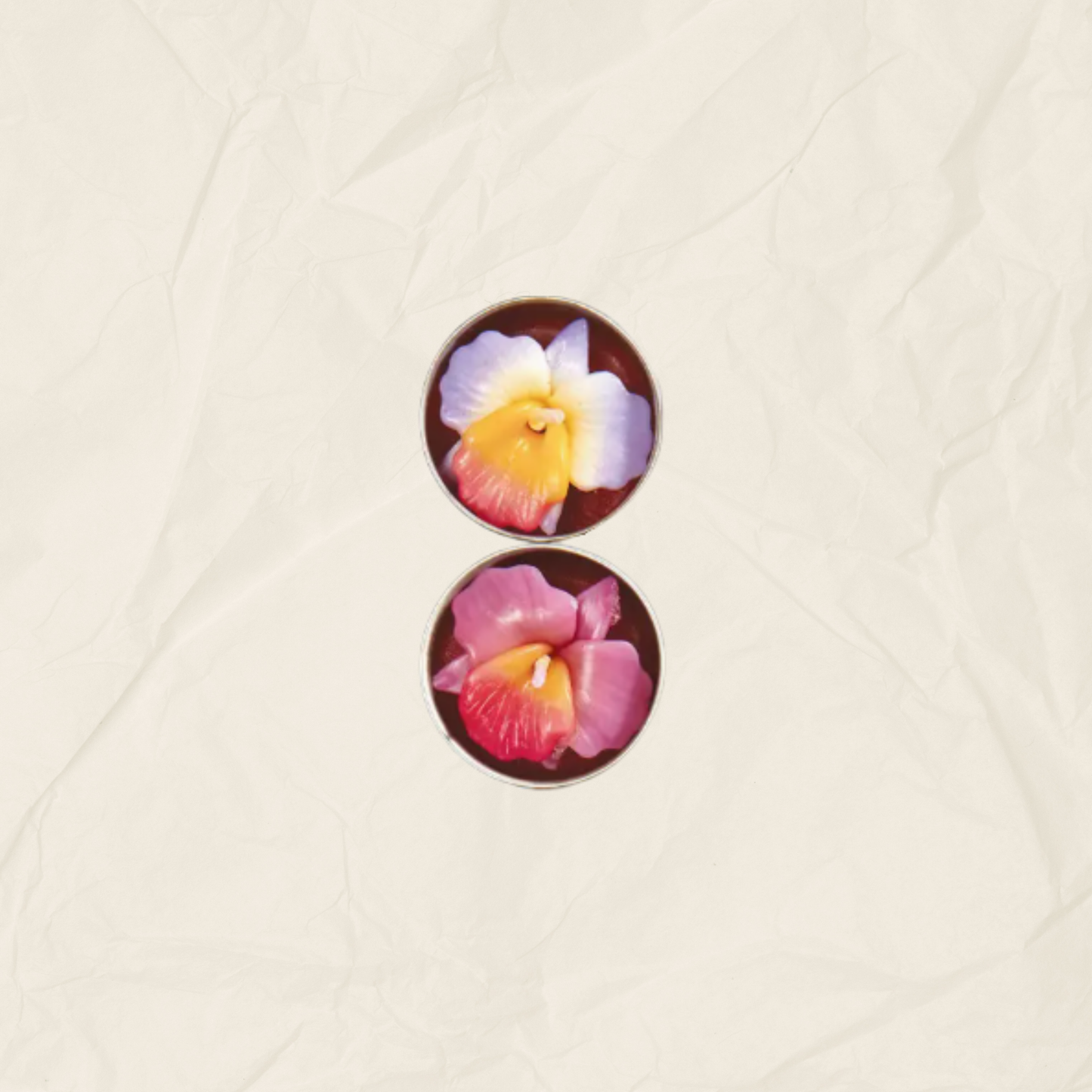 Two tea lights with floral designs, one featuring a white and yellow flower and the other a pink and red flower, displayed on a textured beige background.