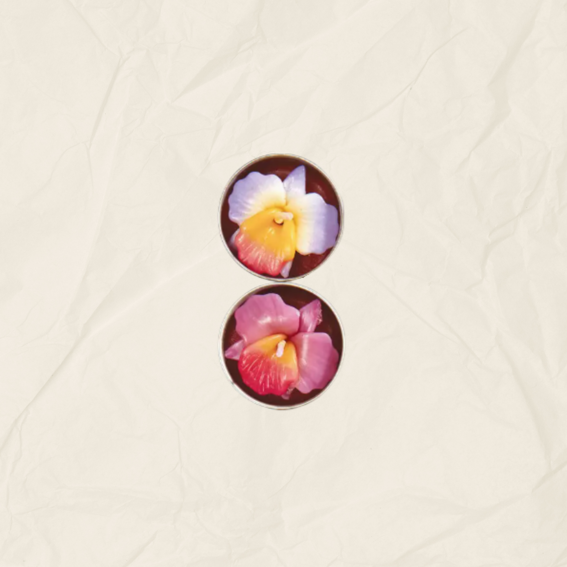 Two tea lights with floral designs, one featuring a white and yellow flower and the other a pink and red flower, displayed on a textured beige background.