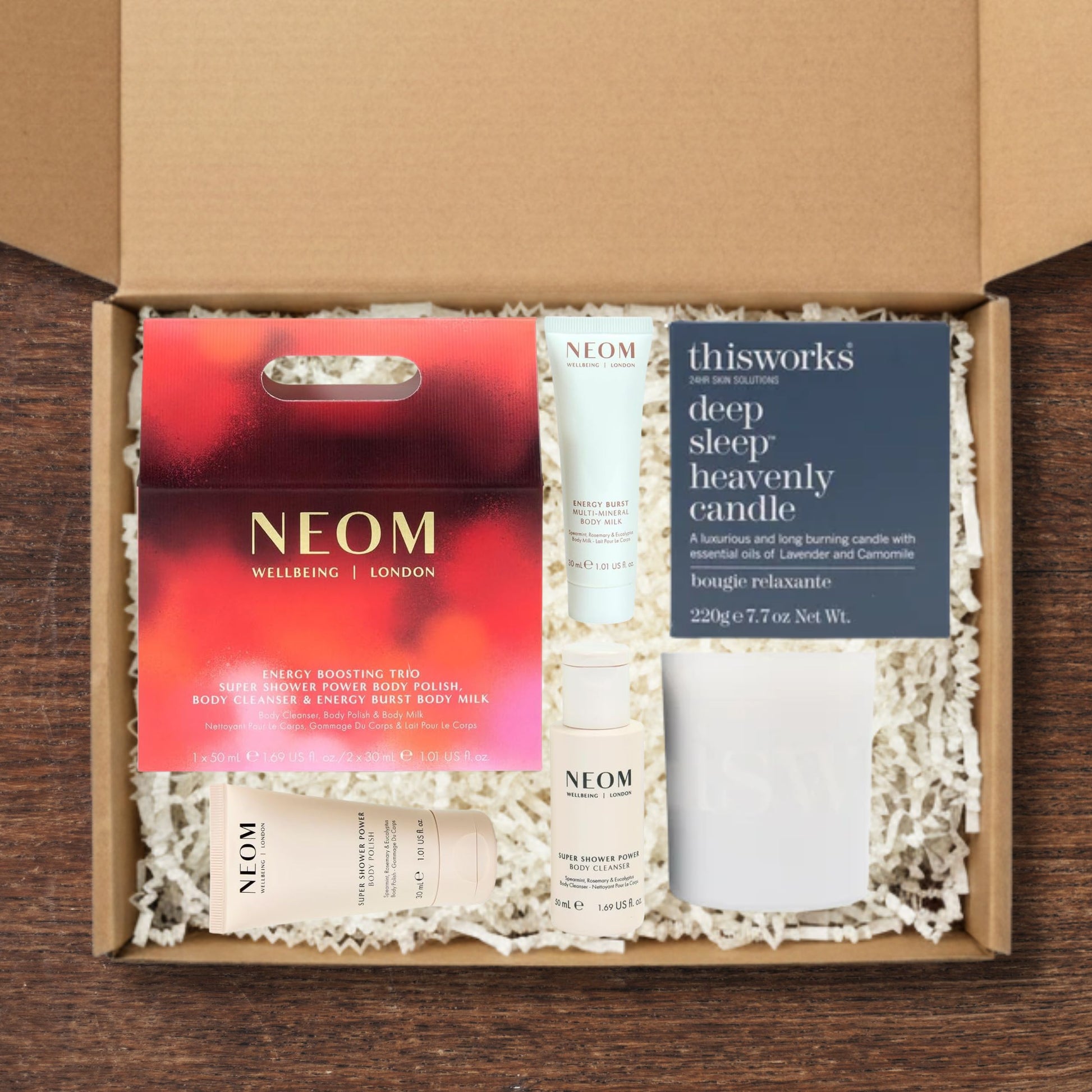 Gift box containng NEOM Energy Boosting Trio Gift Set and a This Works Deep Sleep Heavenly Candle