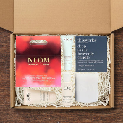 Gift box containng NEOM Energy Boosting Trio Gift Set and a This Works Deep Sleep Heavenly Candle