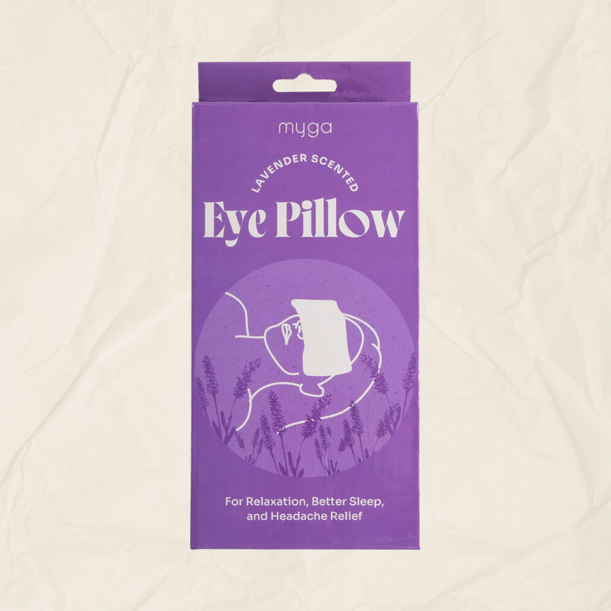 A purple rectangular product box for a myga brand lavender-scented eye pillow, shown against a textured off-white background.