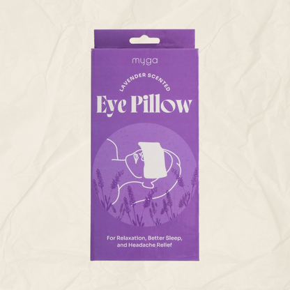 A purple rectangular product box for a myga brand lavender-scented eye pillow, shown against a textured off-white background.