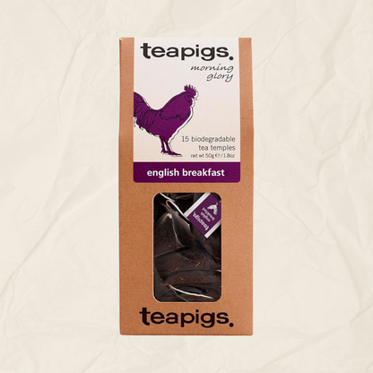 A package of Teapigs English Breakfast tea, featuring a brown kraft paper box with a white label and a purple rooster illustration, set against a textured off-white background.

