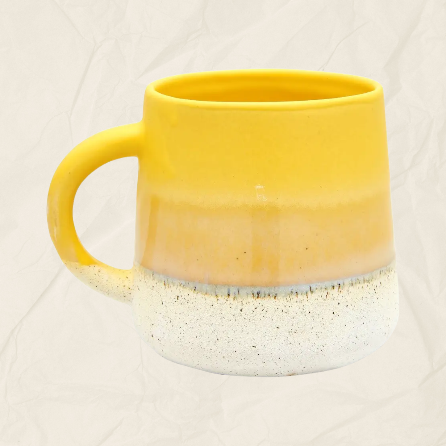 A ceramic mug with a yellow-to-white gradient glaze and a speckled white base, shown against a light beige textured background.